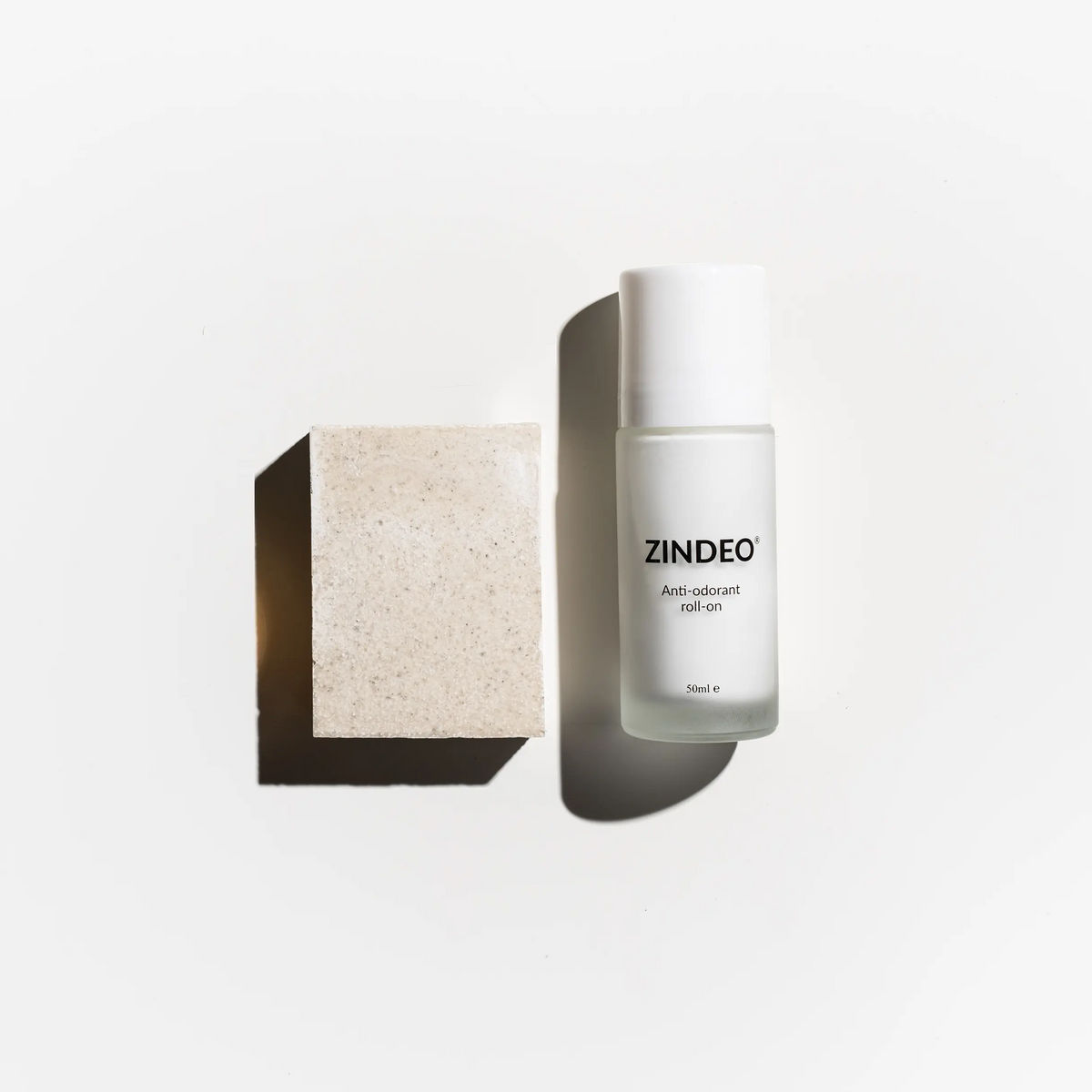 Λευκό μπουκάλι ZINDEO anti-odorant roll-on δίπλα σε μπάρα φυσικού σαπουνιού σε λευκό φόντο