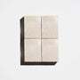 Four square natural beige soap bars arranged in a 2x2 grid on a light background