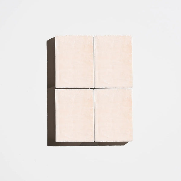 Four square rose-pink natural soap bars arranged in a 2x2 grid on a light background
