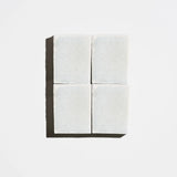 Four square pale green tea tree natural soap bars arranged in a 2x2 grid on a light background