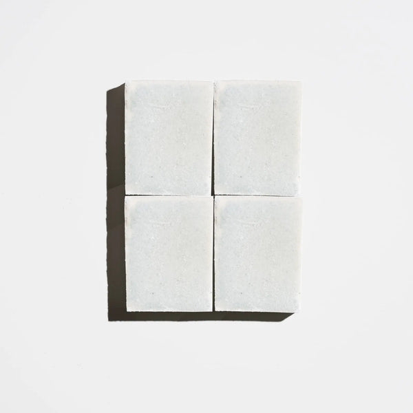 Four square pale green tea tree natural soap bars arranged in a 2x2 grid on a light background
